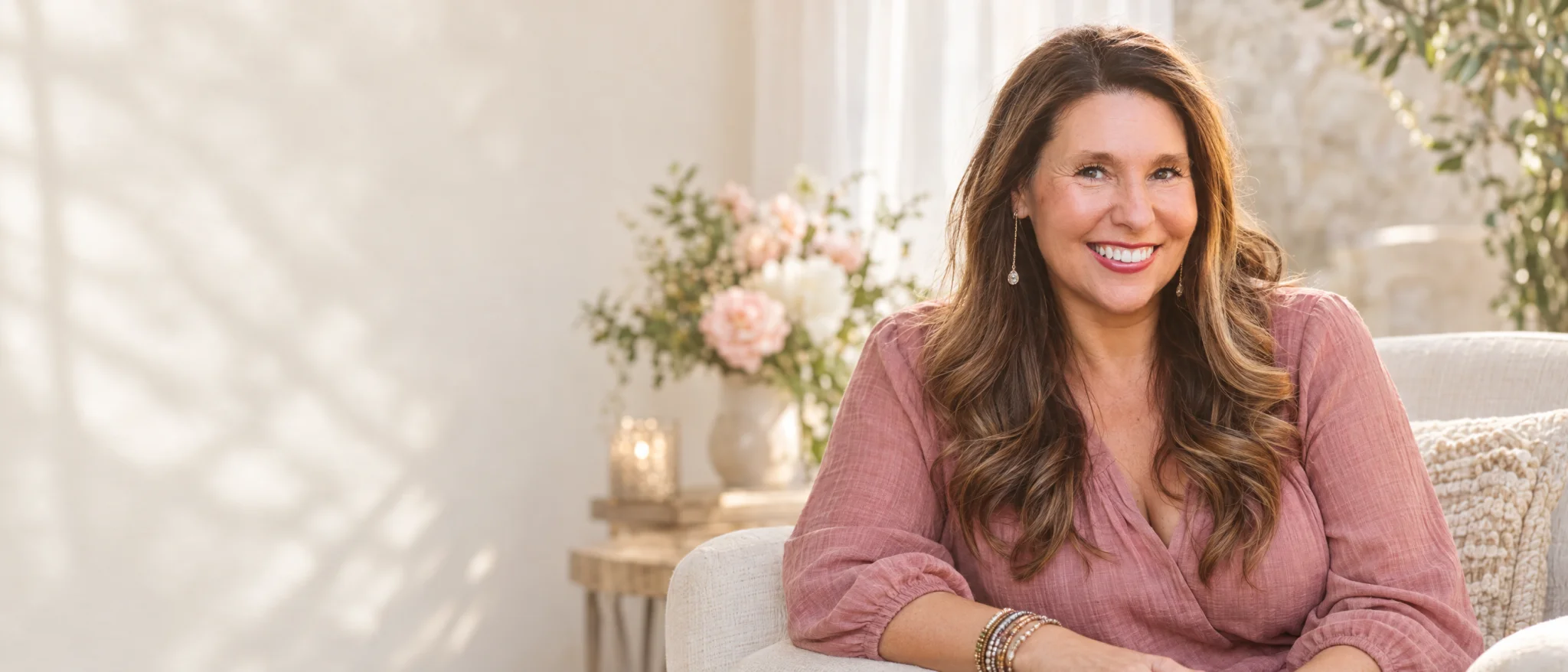 Allison seated in a warm, rose-toned studio setting